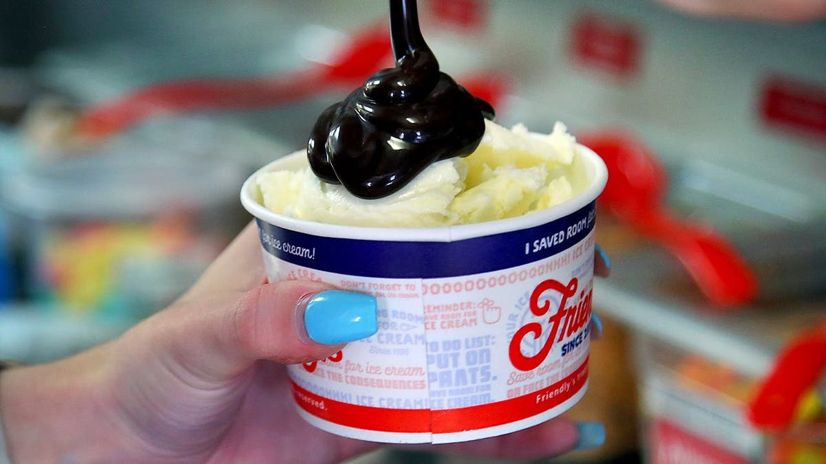 An employee puts hot fudge on a Friendly's sundae.
