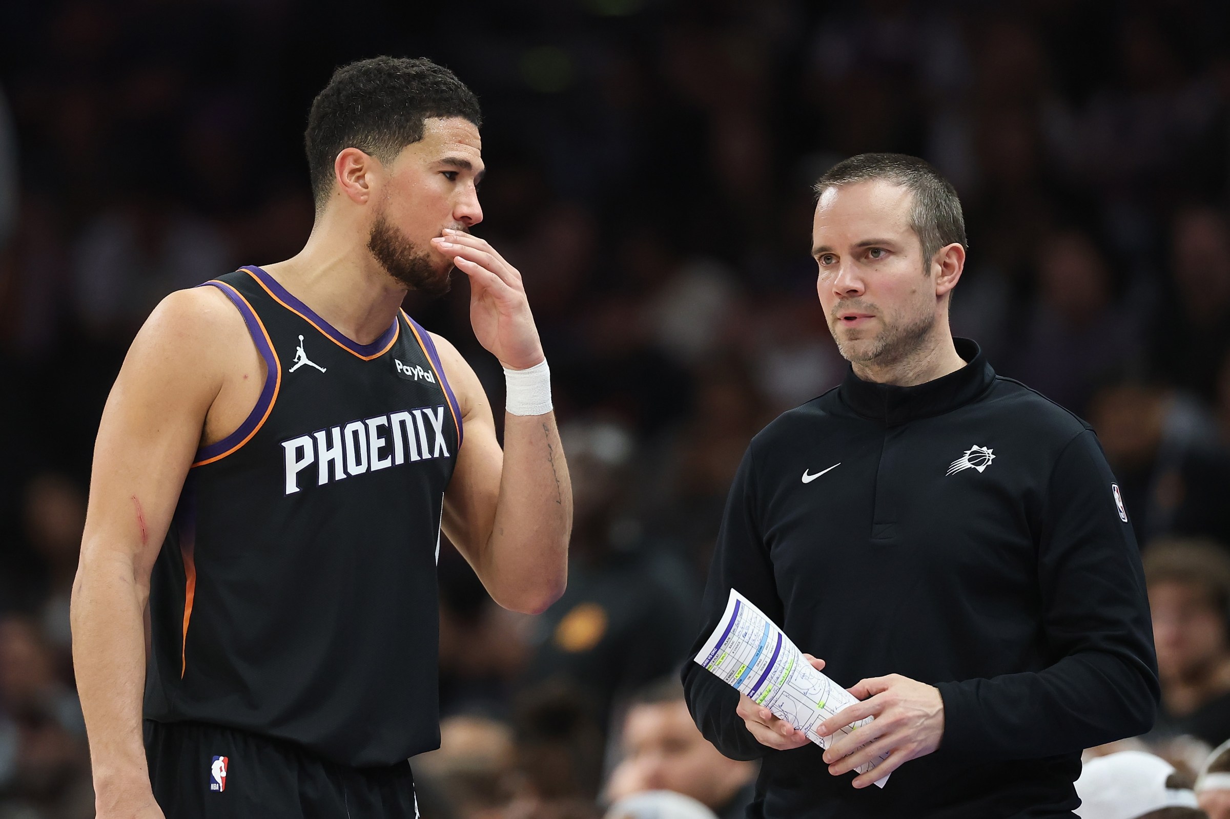 PHOENIX, ARIZONA - JANUARY 04: Devin Booker #1 of the Phoenix Suns talks with head coach Jordan Ott during the second half of the NBA game against the Oklahoma City Thunder at Mortgage Matchup Center on January 04, 2026 in Phoenix, Arizona. The Suns defeated the Thunder 108-105. NOTE TO USER: User expressly acknowledges and agrees that, by downloading and or using this photograph, user is consenting to the terms and conditions of the Getty Images License Agreement. (Photo by Christian Petersen/Getty Images)