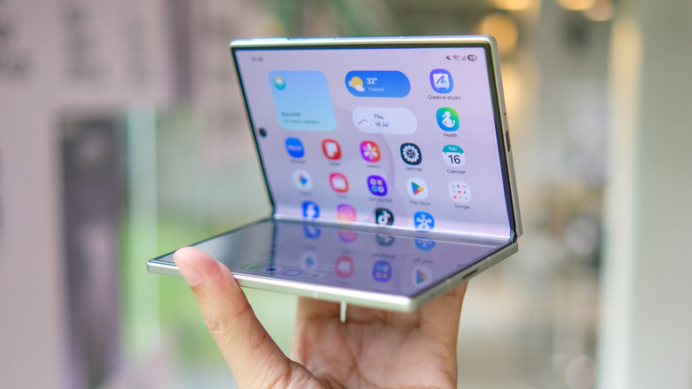 A hand holds a Samsung Fold device.