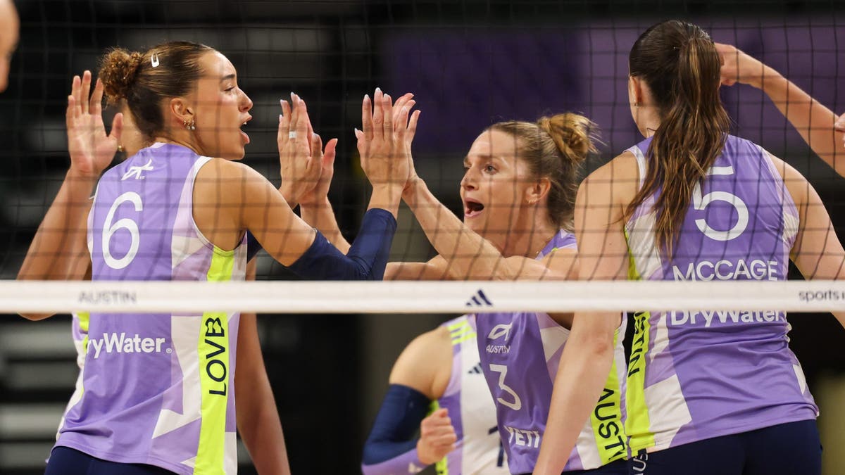 Madisen Skinner and Carli Lloyd high five after a point during a volleyball match.