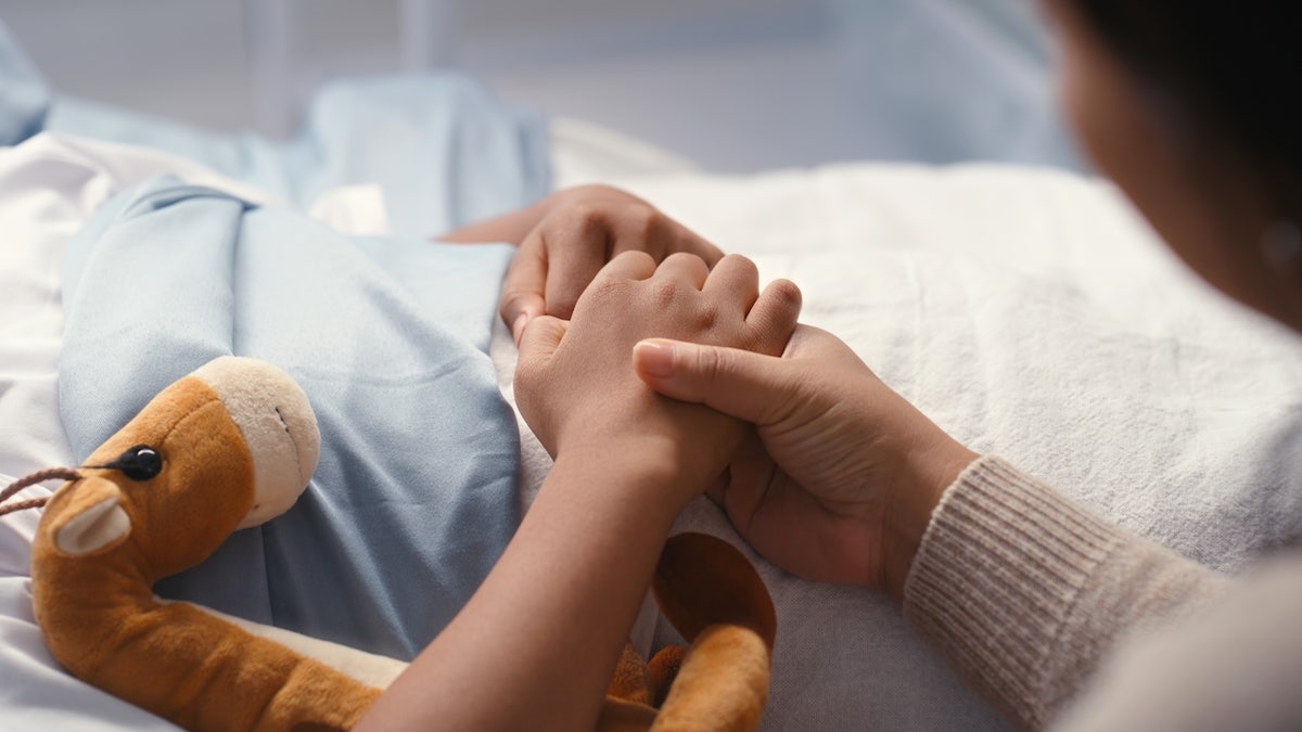Mother holding child's hand in hospital