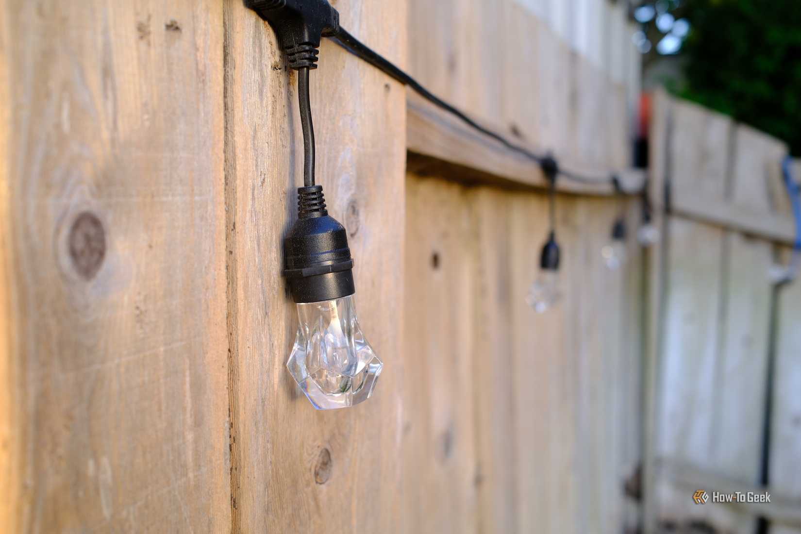 Nanoleaf Essentials Matter Outdoor String Lights hung on a fence.
