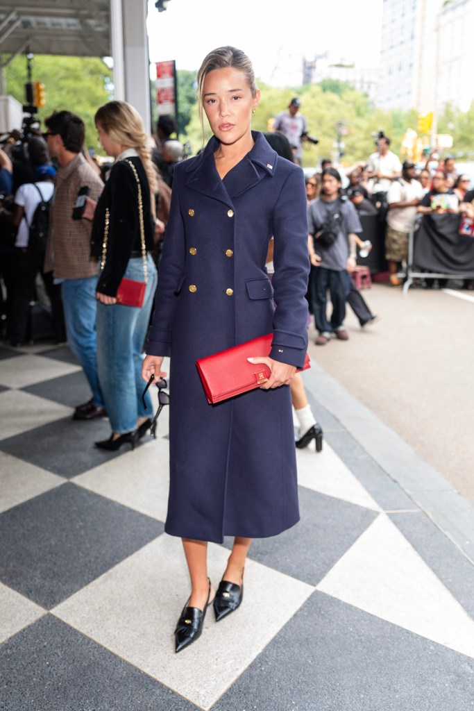 Olivia Ponton attends the Tommy Hilfiger fashion show during New York Fashion Week in a navy coat, red clutch, and black heels.