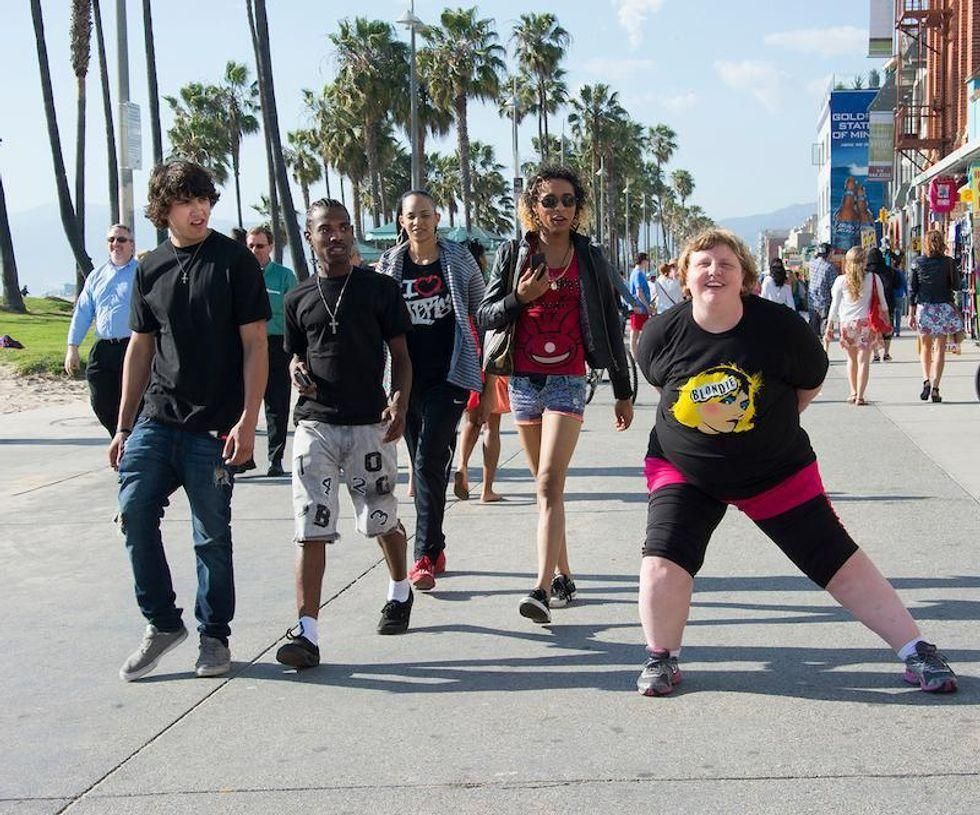A group of young adults passing a heavy set woman and giving her judgmental looks.