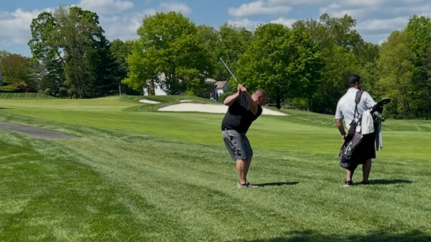 Slyne, left, hitting a shot in his trademark style-- no golf hat, no golf shoes and no gloves.