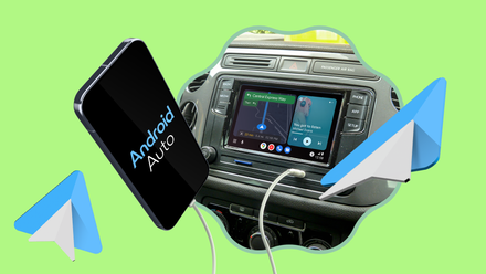 Smartphone connected by a white cable to a car dashboard running Android Auto