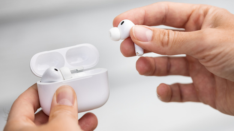 A hand putting the AirPods Pro 3 into a case.
