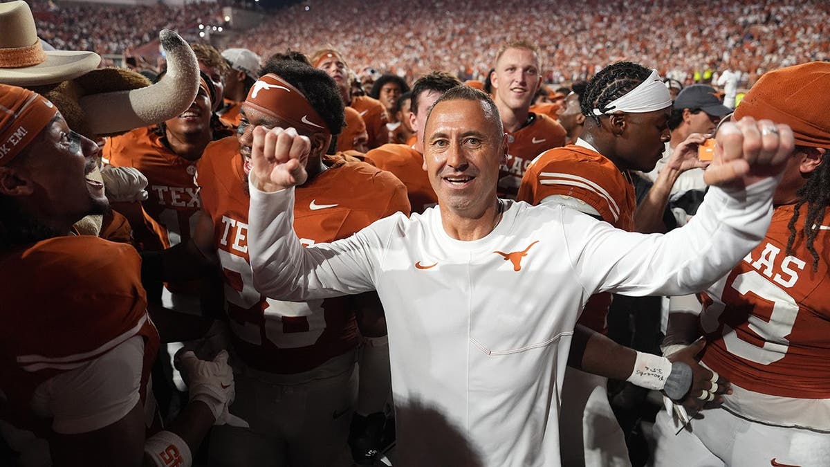 Steve Sarkisian celebrates with Texas players after defeating Ohio State.