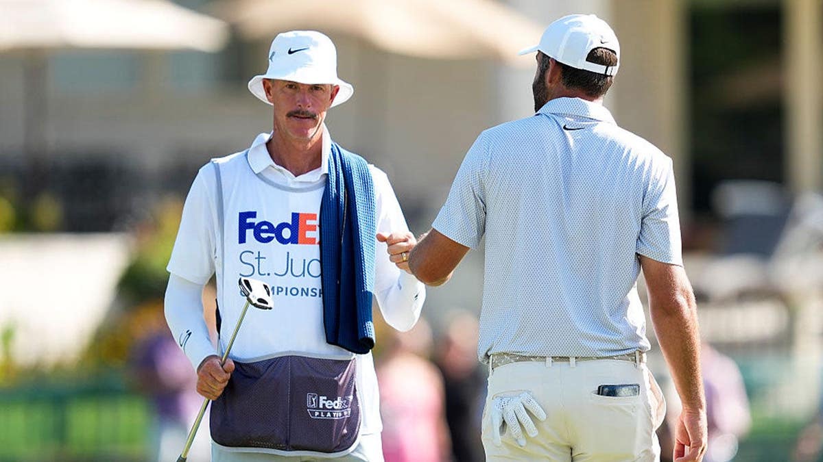 Scottie Scheffler of the United States fist-bumps his caddie Ted Scott on the 18th hole green during the third round of the FedEx St. Jude Championship at TPC Southwind on August 15, 2026 in Memphis, Tennessee.