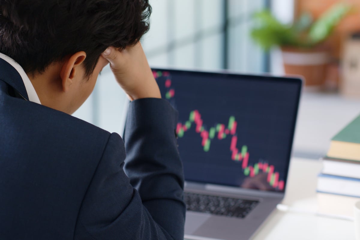 Person with hand on head looking at a chart of a stock price crashing.