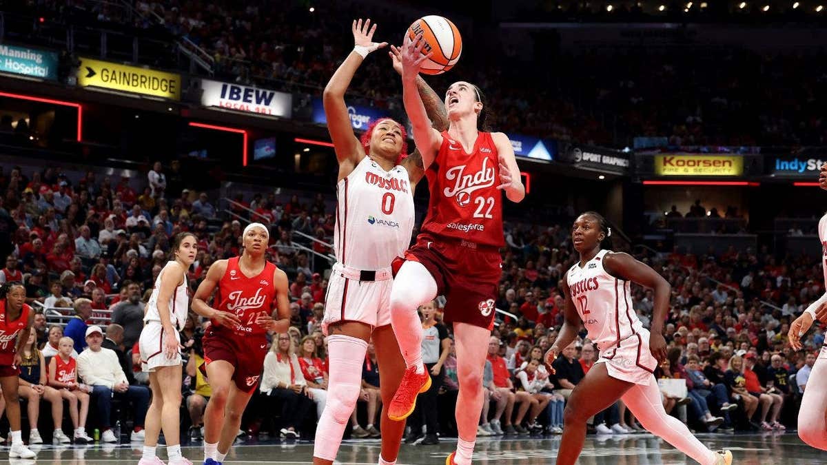 Caitlin Clark shoots while defended by Shakira Austin at Gainbridge Fieldhouse.