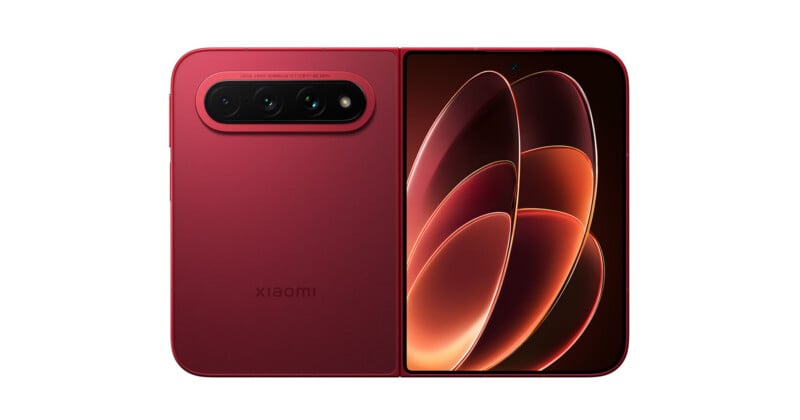 A red Xiaomi foldable smartphone is shown unfolded, displaying a vibrant abstract wallpaper on the right screen and a triple-lens camera module on the left back panel.