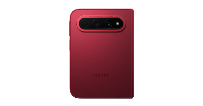 A red Xiaomi foldable smartphone seen from the back, featuring a prominent horizontal camera module with three lenses and a flash.