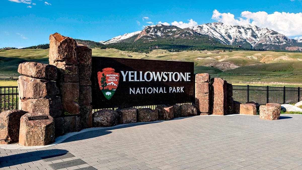 Sign marking the north entrance of Yellowstone National Park with mountains in the background