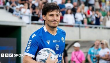 David Silva smiles while holding a football