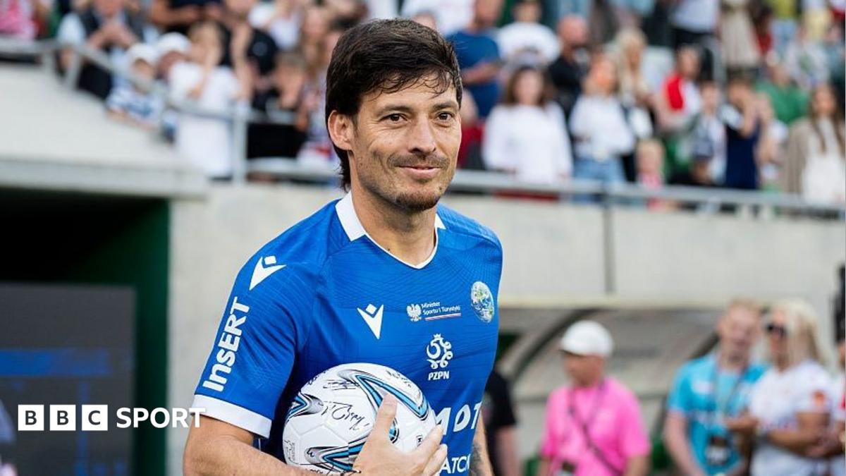 David Silva smiles while holding a football