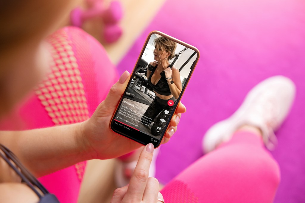 A woman looking at a fitness video on social media on her smartphone.