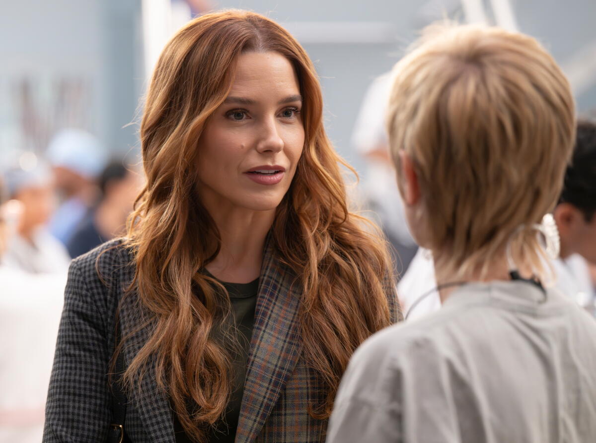 Wearing a tartan blazer, Sophia Bush appears in a promotional image from 'Grey's Anatomy' season 22.