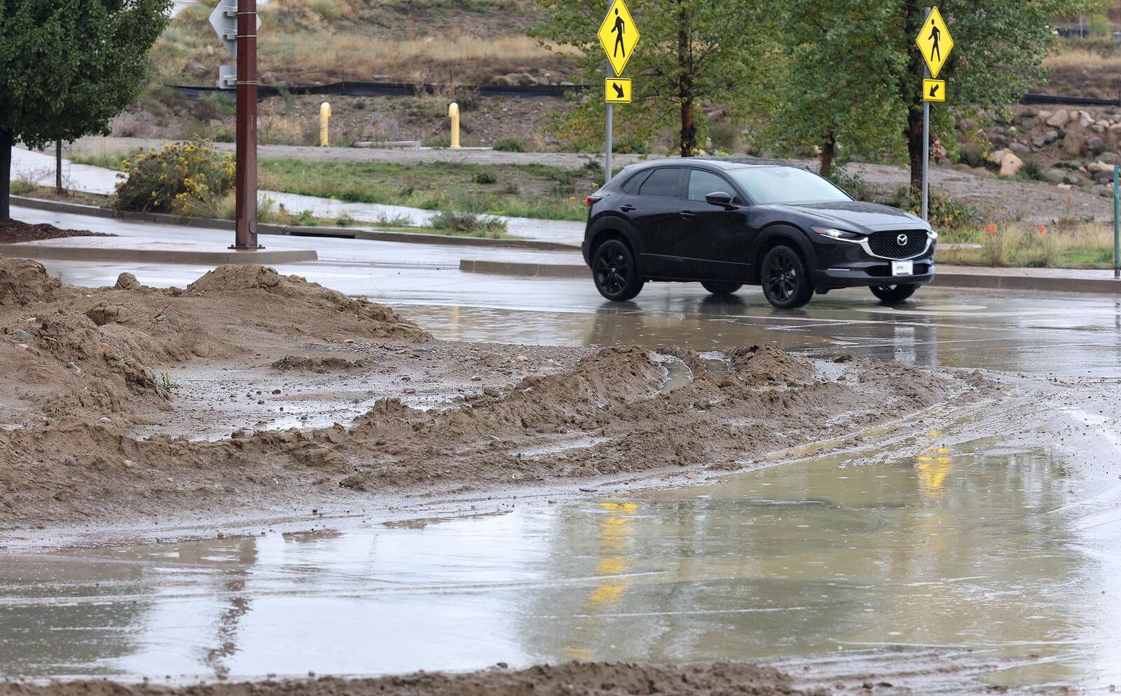Drivers make their way around a flooded lane and mud Wednesday in the Wilson Gulch roundabout in Grandview. (Jerry McBride/Durango Herald)