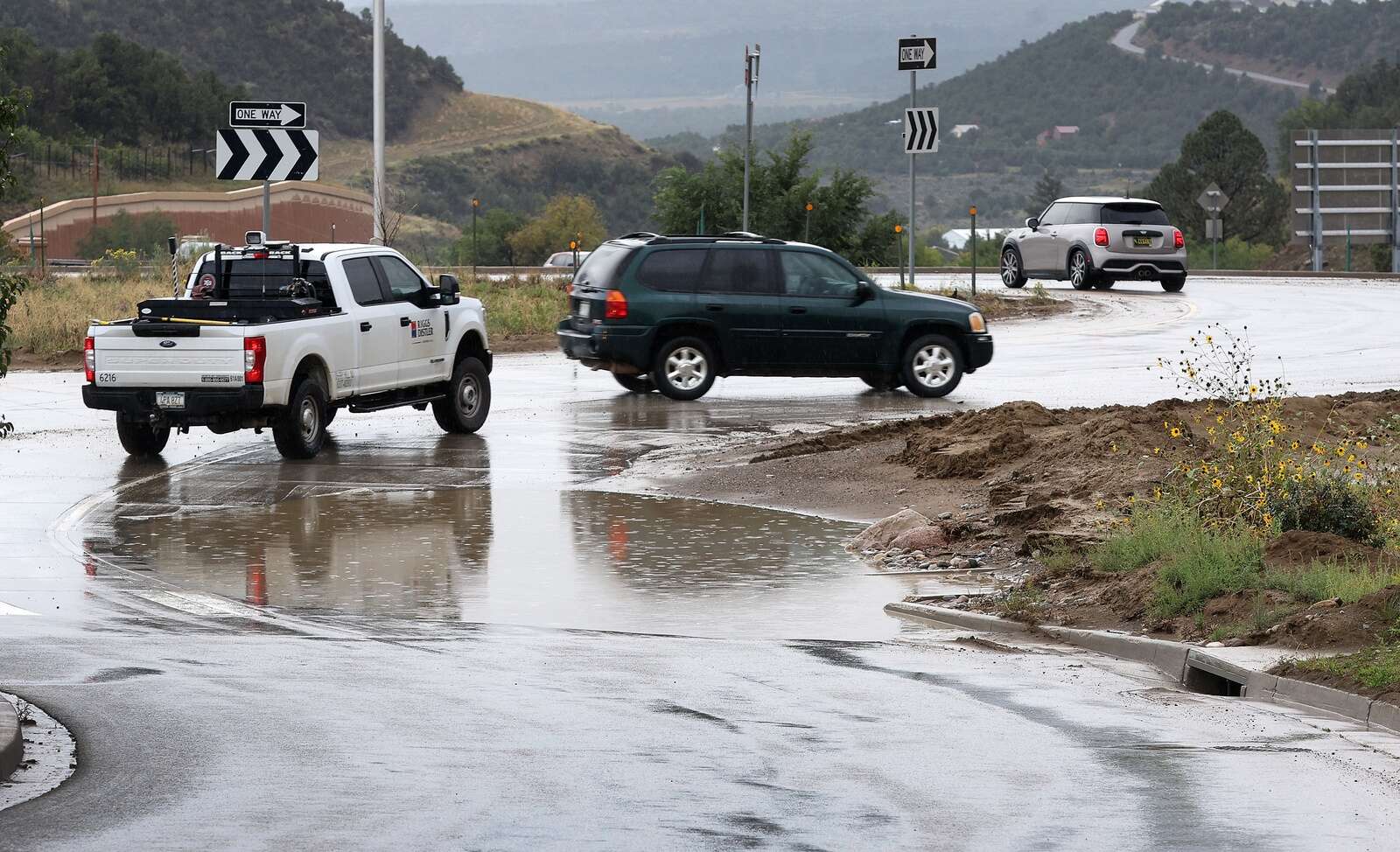 Drivers make their way around a flooded lane and mud Wednesday in the Wilson Gulch roundabout in Grandview. (Jerry McBride/Durango Herald)