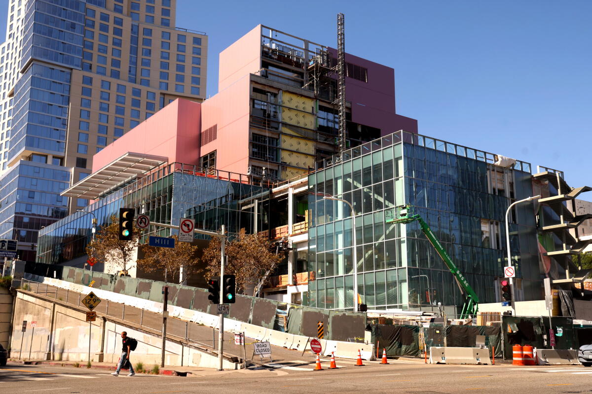 A pedestrian walks past a building under construction in downtown L.A.