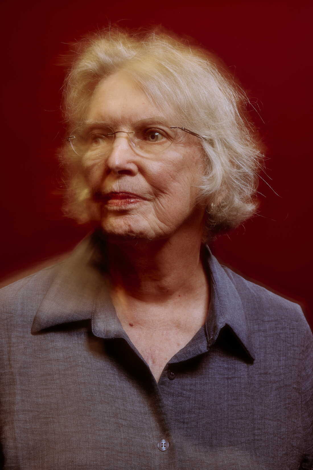 Lowry is photographed against a red background with a slight yellow haze around her face.