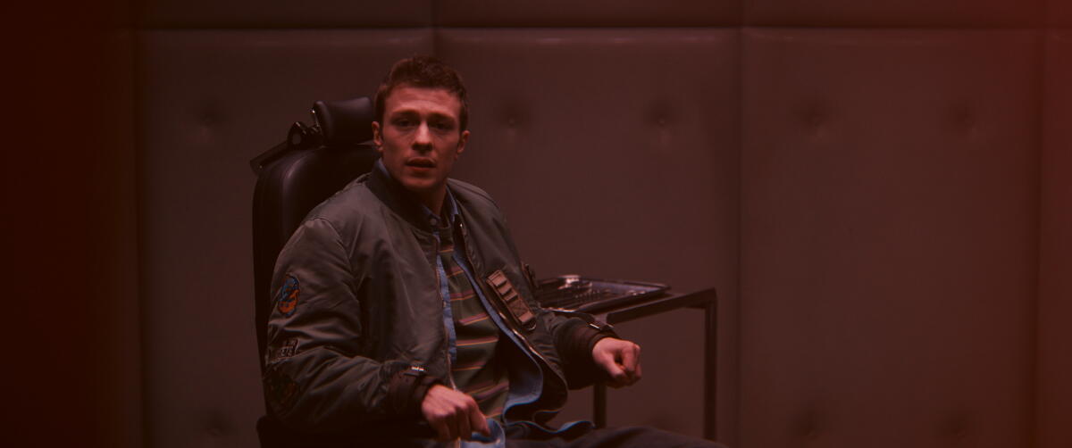 Ruaridh Mollica as Tommy Shepherd cuffed to a chair.