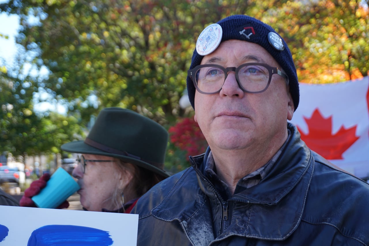A man with a beanie with several pins stuck to it.