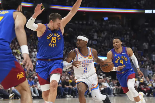 Oklahoma City Thunder guard Shai Gilgeous-Alexander, center, drives to the basket as Denver Nuggets center Nikola Jokic, left, and guard Russell Westbrook defend in the second half of Game 3 in the Western Conference semifinals of the NBA basketball playoffs Friday, May 9, 2025, in Denver. (AP Photo/David Zalubowski)