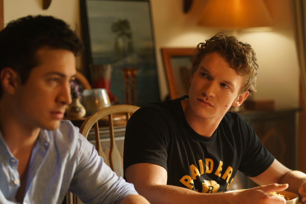 "Heated Rivalry" stars Hudson Williams and Connor Storrie sit together at a table.