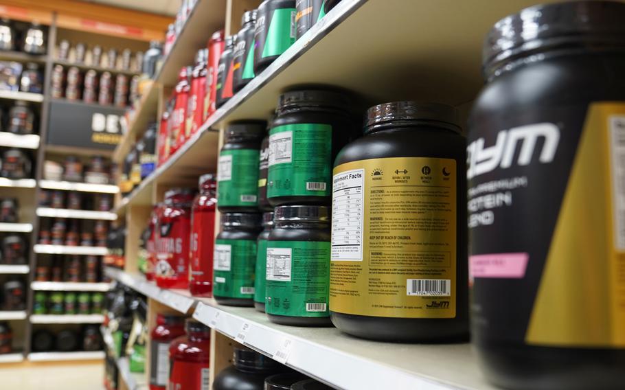A close-up view of multi-colored bottles of nutritional supplements stacked on a store shelf.