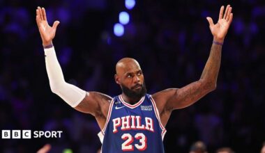 Lebron James, wearing a blue vest with Phila 23 in white text, holds his arms in the air