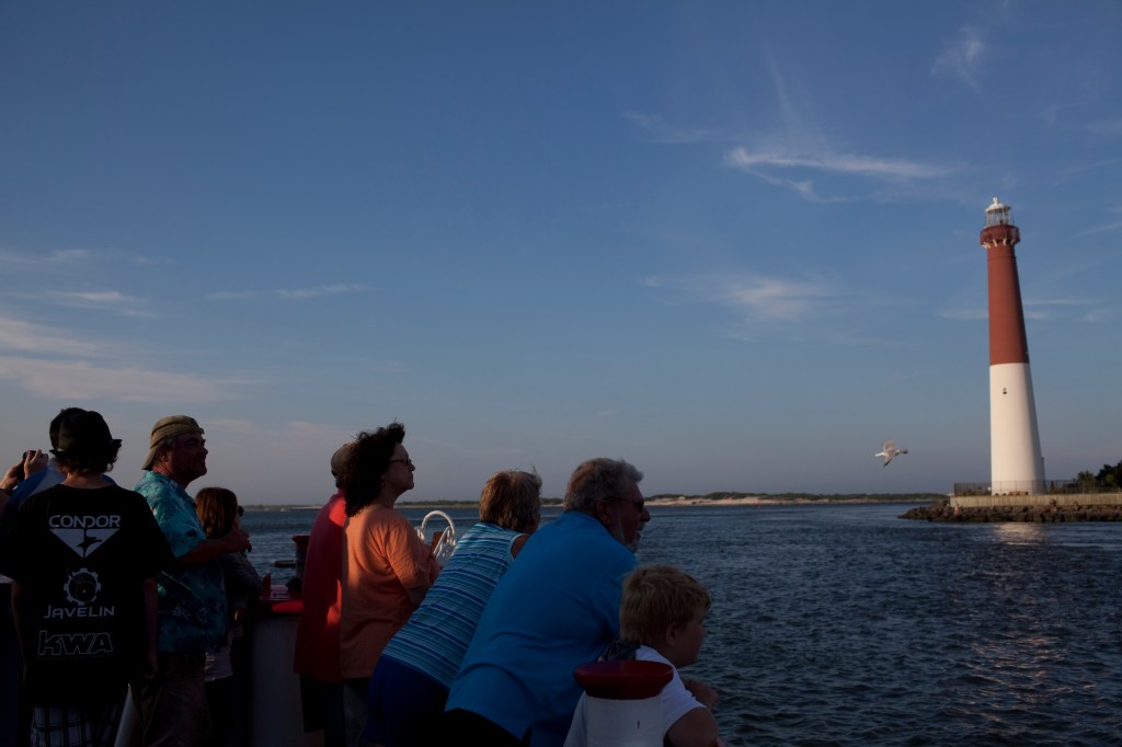 Visitors on the Miss Barnegat Light sunset cruise sail past the Barnegat Lighthouse on the northern tip of Long Beach Island.