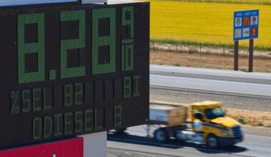 Semis drive past sign showing fuel prices