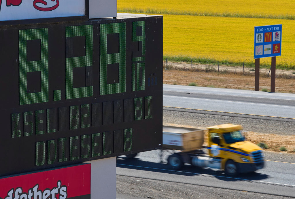 Semis drive past sign showing fuel prices