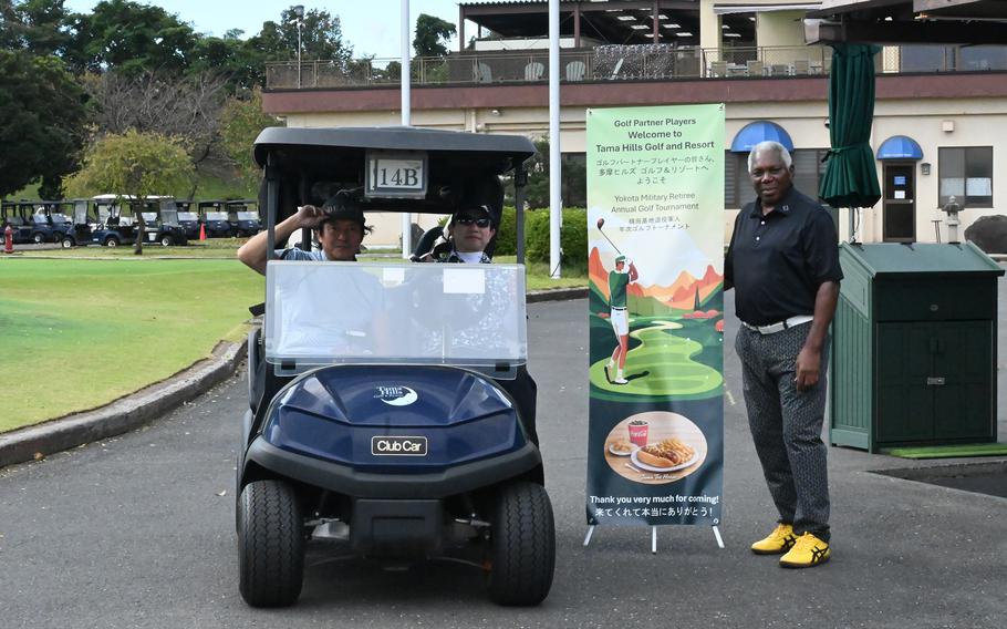 Participants pose in a golf cart beside a welcome sign for the Yokota Military Retiree Annual Golf Tournament at Tama Hills Golf and Resort in Japan.