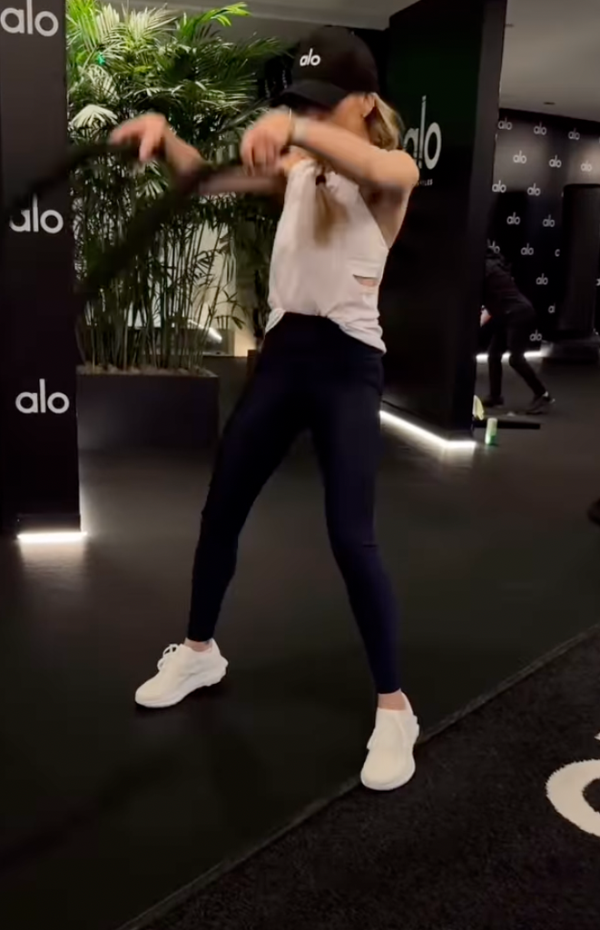 Sarah wears a black sleeveless top and burgundy leggings