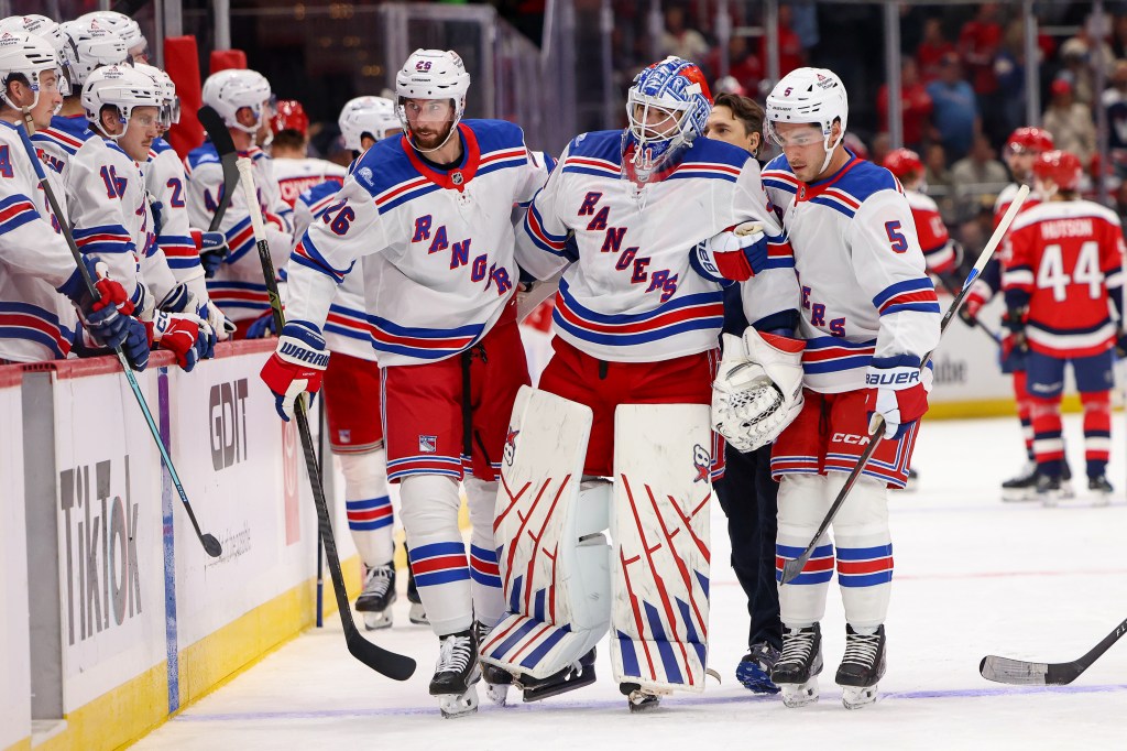 Rangers goaltender Igor Shesterkin (31) is helped off the ice by Marcus Pettersson (26) and Sean Durzi after suffering an injury during an NHL game against the Washington Capitals at Capital One Arena in Washington, D.C., Friday, Oct. 9, 2026.