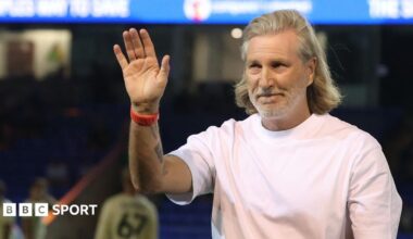 Robbie Savage in a white t-shirt watching Peterborough against Ipswich Under-21s from the touchline
