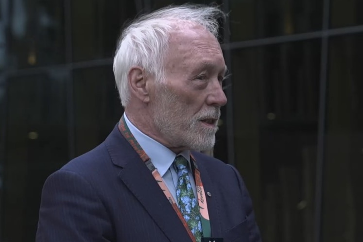 Man in suit stares to the side of the camera