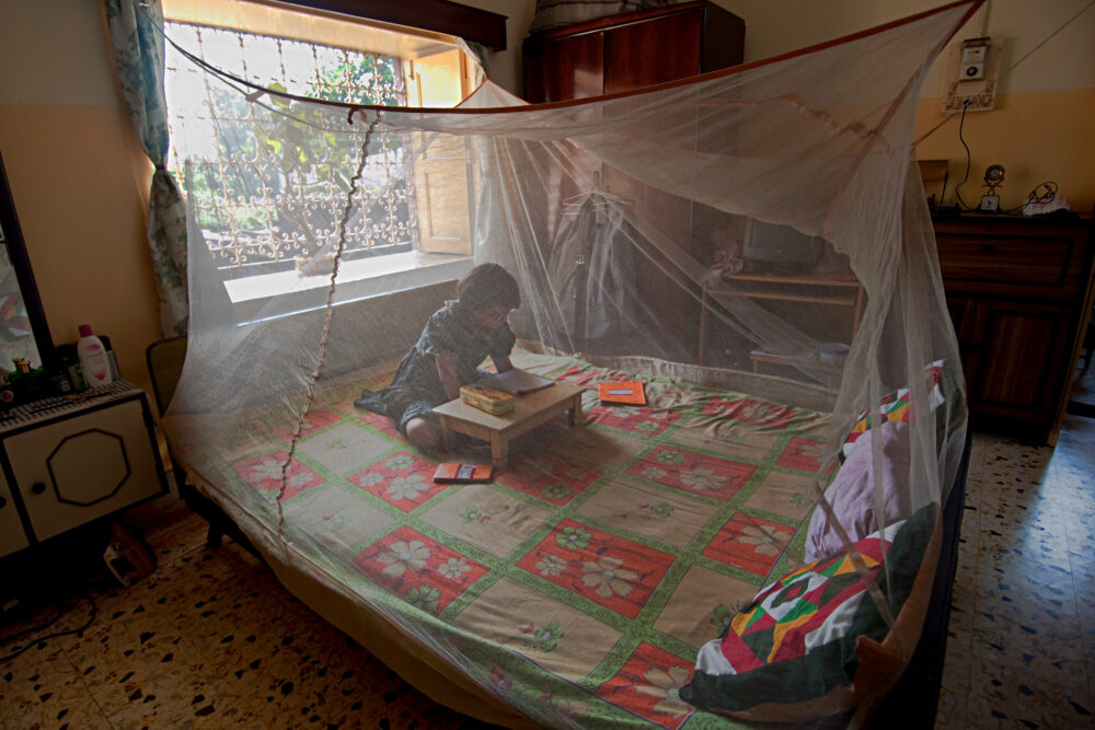 A child sits beneath an antimalarial net. As major donors reduce funding, global health initiatives navigate ongoing financial uncertainty.