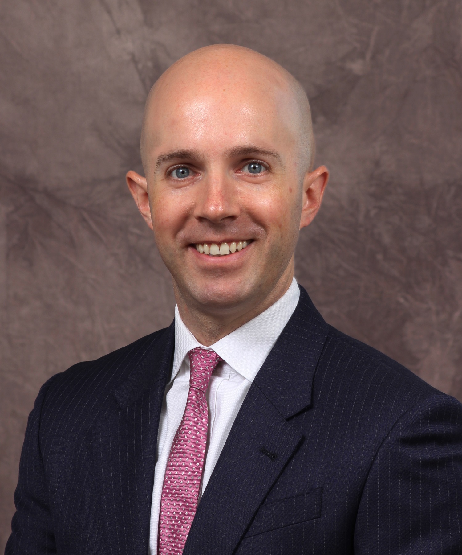 A photo of a bald man wearing a business suit.