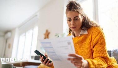 Woman looks at a bill in her living room.