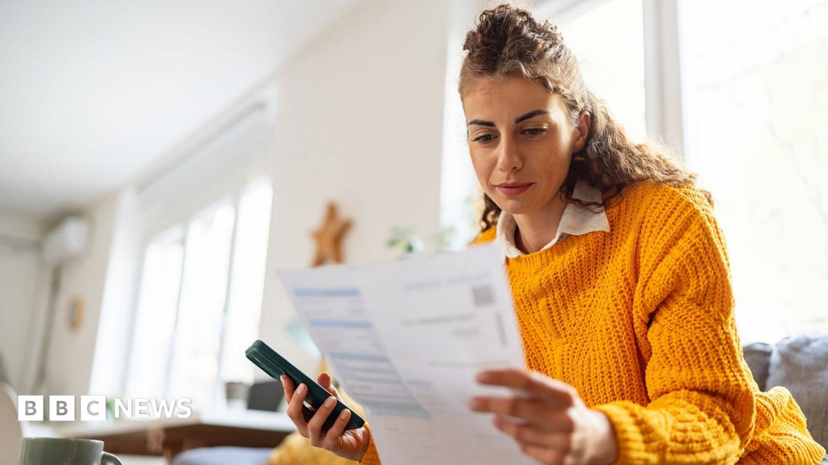Woman looks at a bill in her living room.