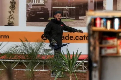 One of two armed Palestinian men walks with an assault rifle during a fire exchange with Israeli forces at the northern checkpoint of Hebron in the West Bank on Friday.