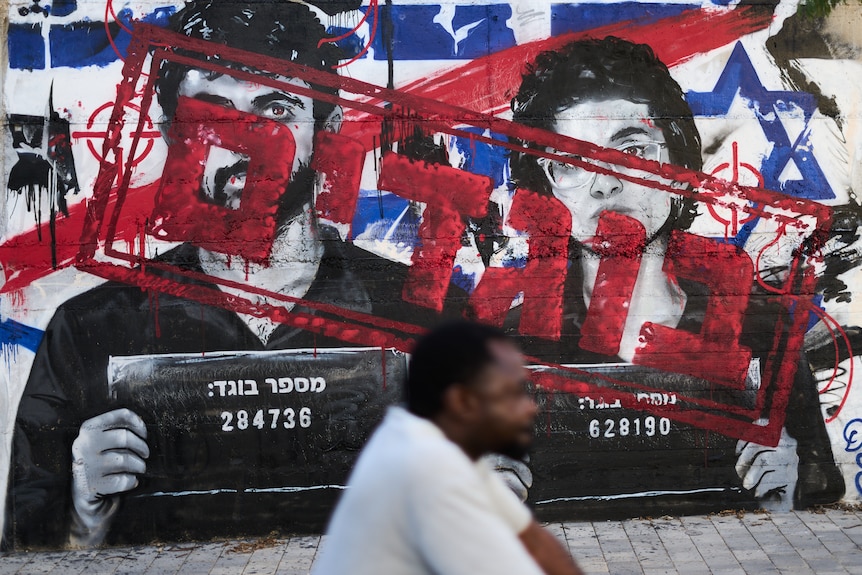 A mural of a man and a woman with red writing graffitied on top accusing them of being traitors to Israel.