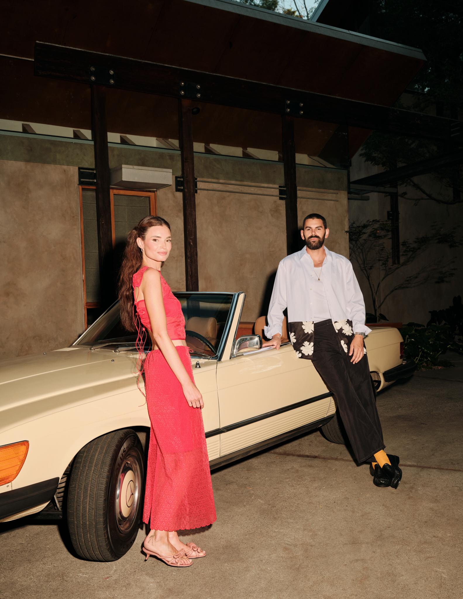 man and woman outside building in front of retro car