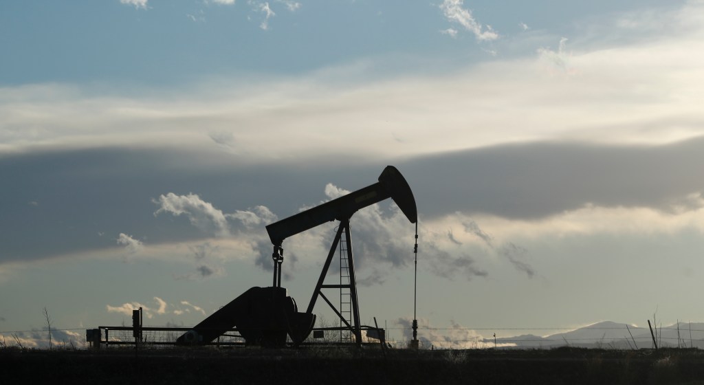 FILE--In this Saturday, Dec. 22, 2018, file photograph, a pump jack is shown over an oil well along Interstate 25 near Dacono, Colo. traffic flows on Interstate 25 into downtown Denver. (AP Photo/David Zalubowski)
