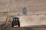 A tractor carrying a bale of hay and kicking up some dust on a dry but picturesque farm in Central Western NSW, Australia.