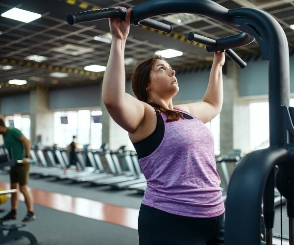 woman doing pull-ups in gym